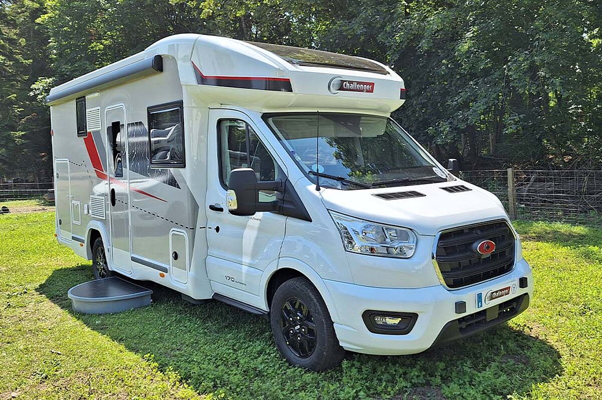 Weißes Wohnmobil mit roten Details auf einer Wiese.