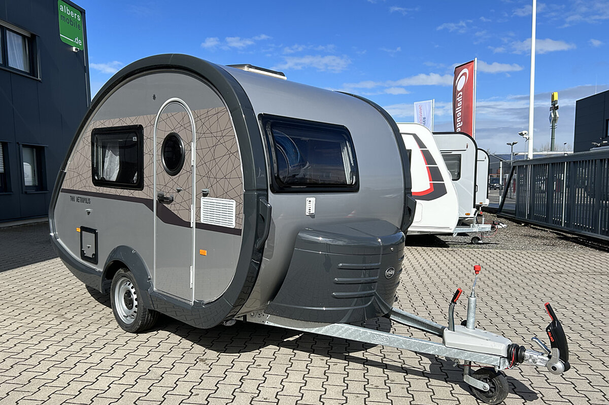 T@b-Wohnmobile sind nicht nur praktisch, sondern auch stilvoll und modern gestaltet. Grauer Wohnwagen mit dunklen Details und einer runden Form auf einem Parkplatz.