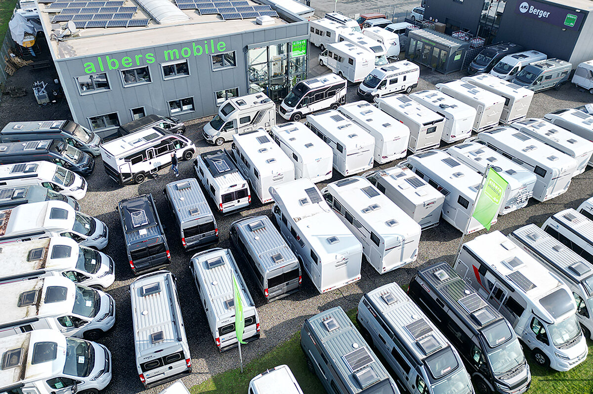 Viele verschiedene Wohnwagen und Wohnmobile vor dem Firmengebäude von Albers Mobile.