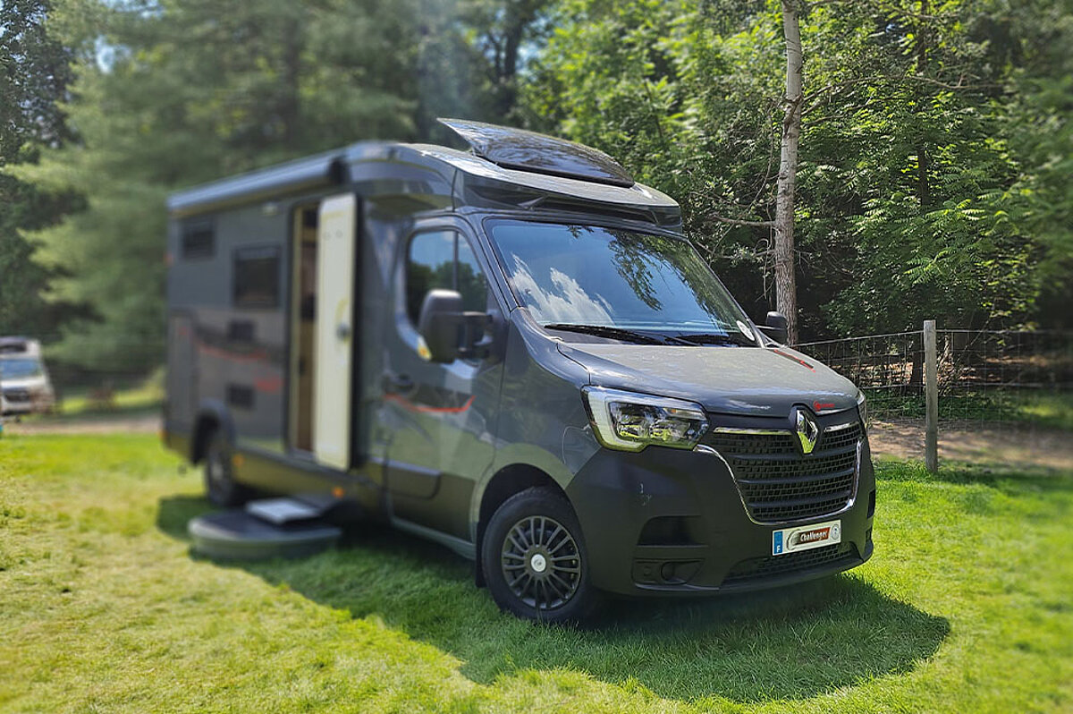 Schwarze Wohnmobil auf einer Wiese mit geöffneter Tür.