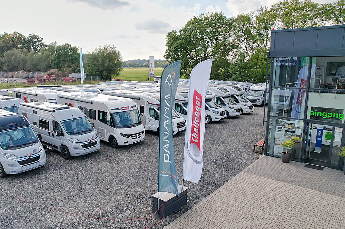 Mehrere Wohnmobile vor einem Gebäude.