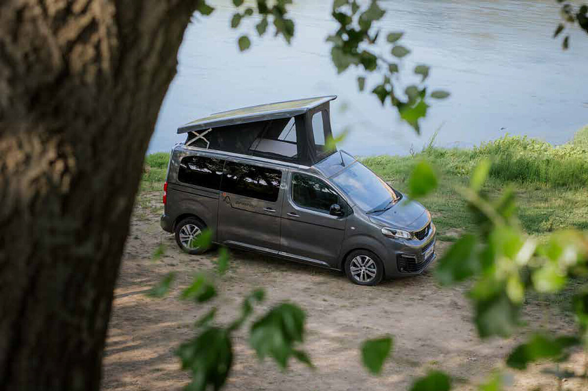 Blick von oben auf einen Campervan mit aufgestelltem Dach.