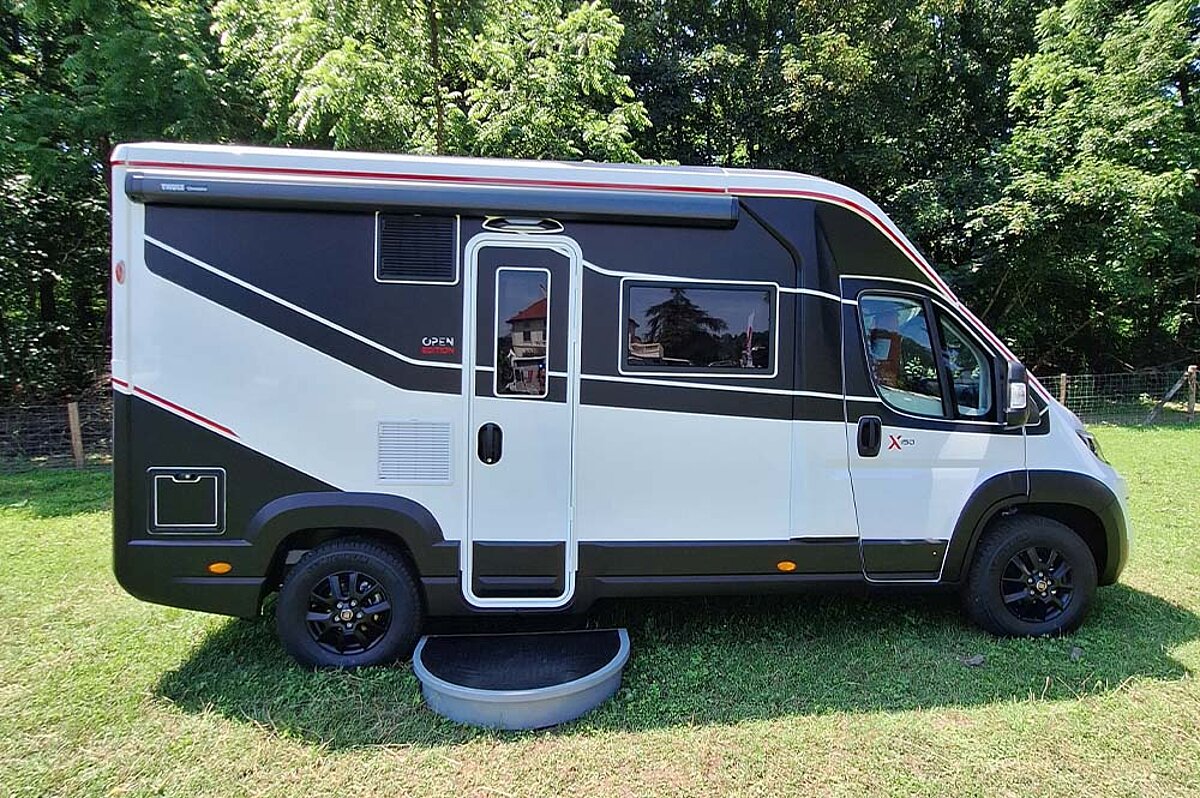 Schwarz-weißes Wohnmobil auf einer Wiese.