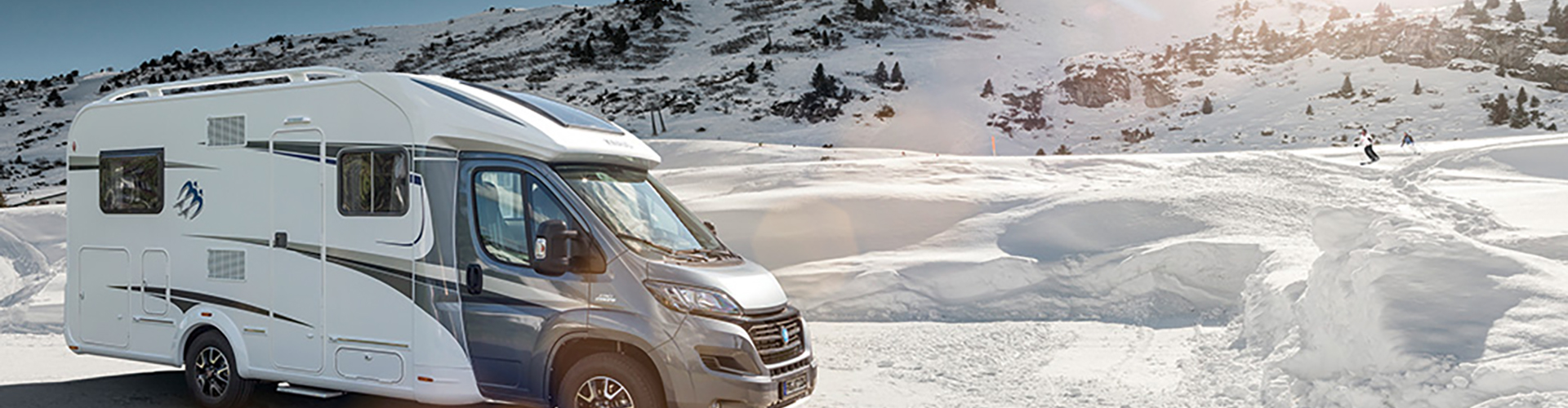 Wohnmobil vor einer Winterlandschaft.